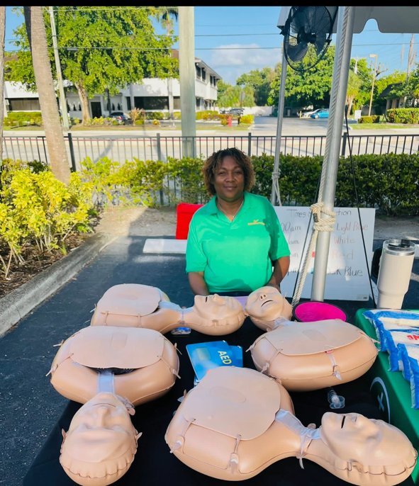 Hour Helping Hands instructor at an outdoor training table with adult and infant CPR manikins